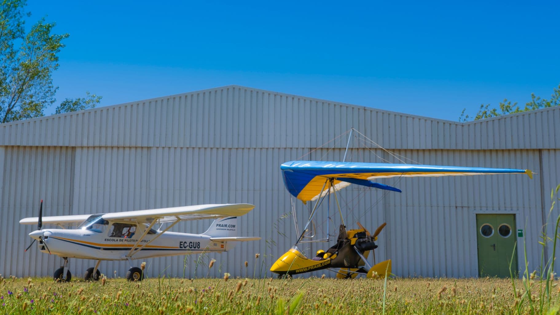 Avioneta y trike de la escuela frente al hangar